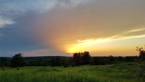 Storm clouds pass over sky creating a blazing sunset